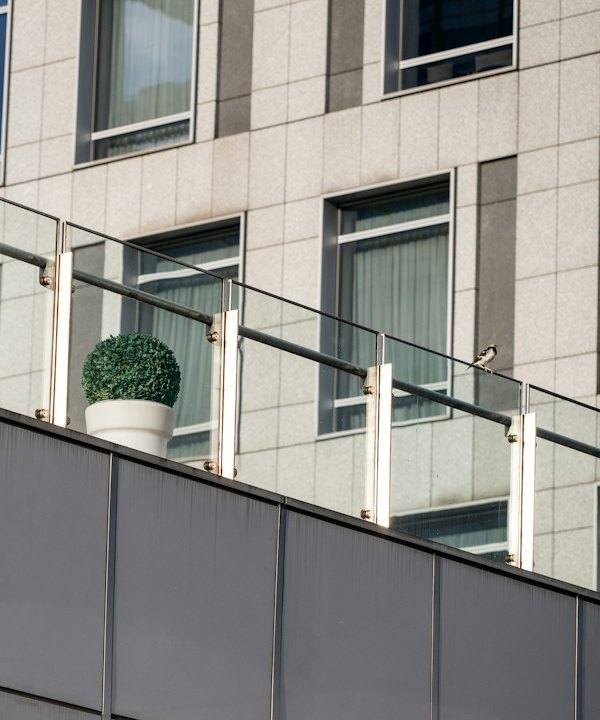 Garde-corps en verre à poteaux métalliques au bord d’une terrasse d’immeuble