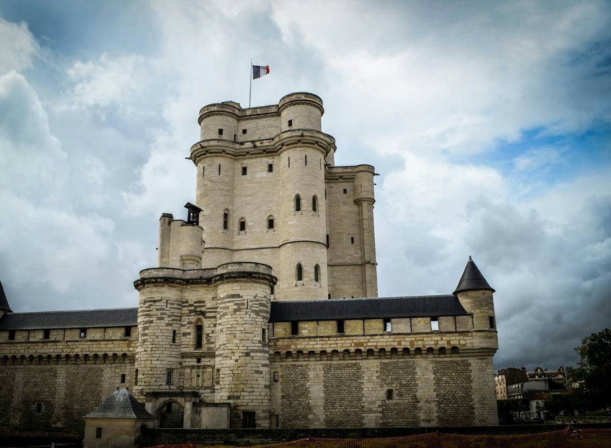Donjon du château de Vincennes sous un ciel chargé, drapeau français au sommet